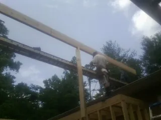 Carpenter setting a ridge beam over a new addition frame — Ice Dam Removal by Roofing Brothers in Cade