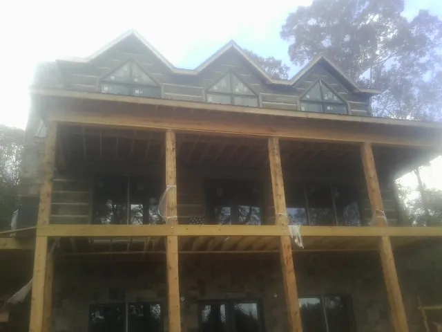 Dormers and porch framing on a large log home under construction — Roof Coating work by our crew in Cade