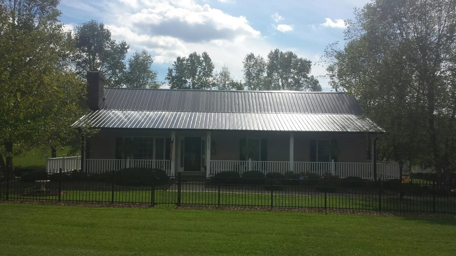 Gray metal roof on a brick ranch with a full width front porch — Gutter Guard Installation work by our crew in Cade